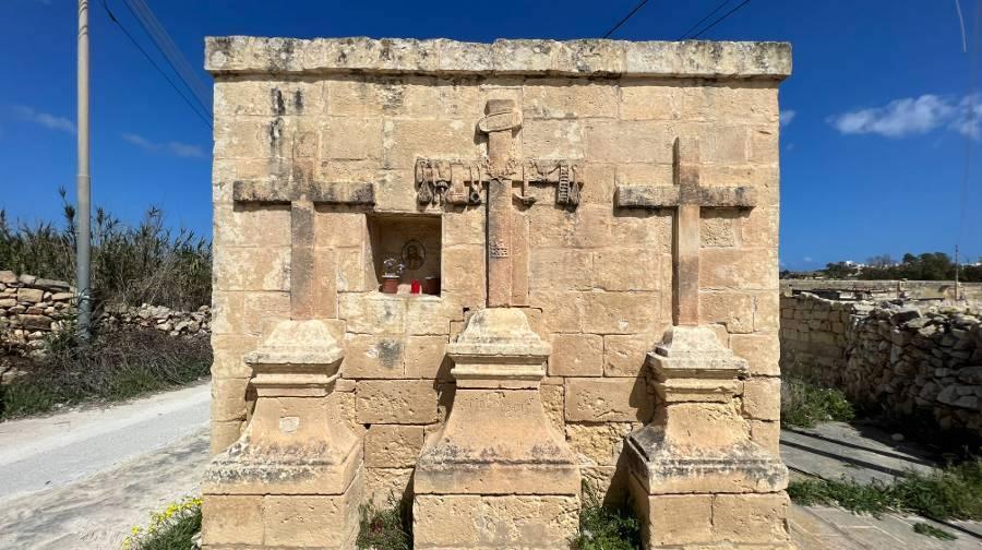 The monument of the three crosses, a limestone wall with three crosses of varying sizes sculpted out of it. The middle cross has many symbols on it.