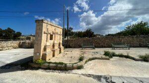 A standalone small wall in the middle of the countryside with three crosses on it