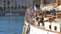 An old style white sailboat with people on deck