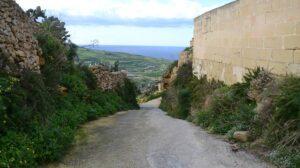 A road in Gozo with the relief of the island seen at the back