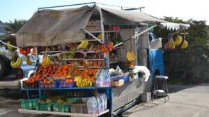 A local farmer selling produce from a stand perched on the back of an open car