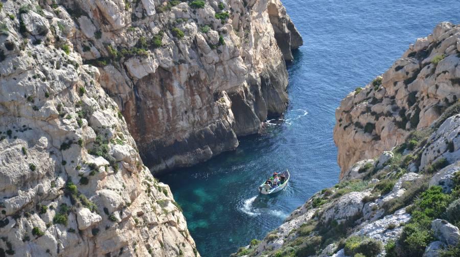 A cove with rocky walls seen from above and a small boat floating in it