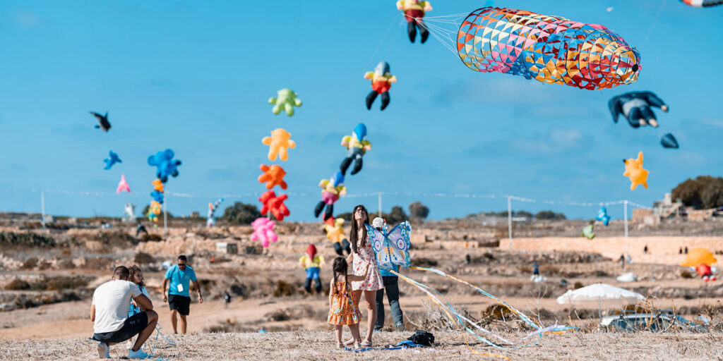 Blue skies speckled with rainbow colored kites at Gozo Kite and Wind Festival