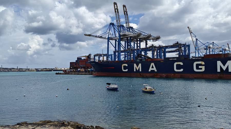 Industrial, heavyweight ships in red and blue with cargo on them and accompanying machinery parked at sea