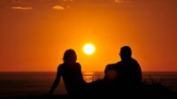 A sunset silhouette of a couple overlooking the beach near the Blue Grotto View Point.