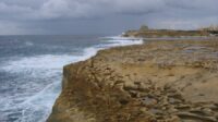 Xwejni Bay in winter, crashing waves on a rock beach